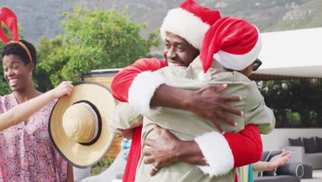 Feliz-Grupo-De-Amigos-Diversos-Abrazándose-En-La-Fiesta-De-Navidad-En-El-Jardín