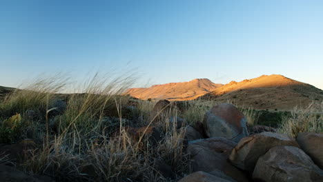 hunter on hill overlooking karoo landscape sits down and aims with rifle