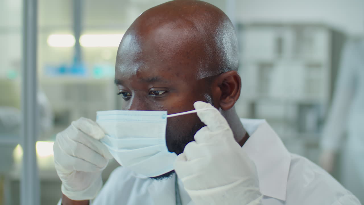 African American Scientist Putting on Mask and Glasses in Lab