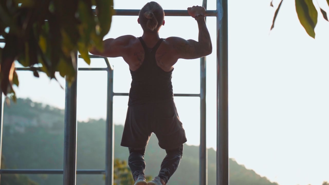 Muscular Man Performing Pull-Ups on Outdoor Calisthenics Bar