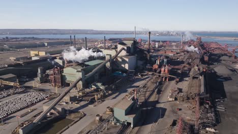 an industrial steel mill in hamilton, ontario, with plumes of steam and machinery, aerial view