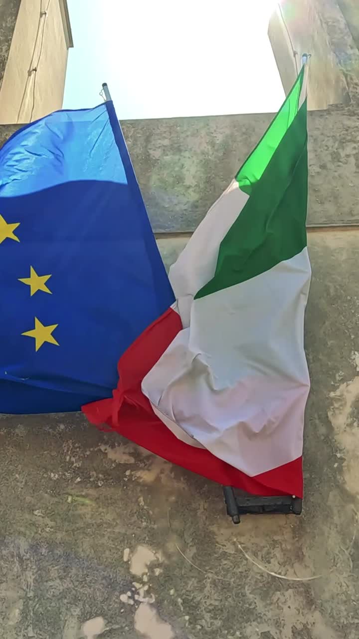 Bandiere europea e italiana che sventolano alla luce del sole