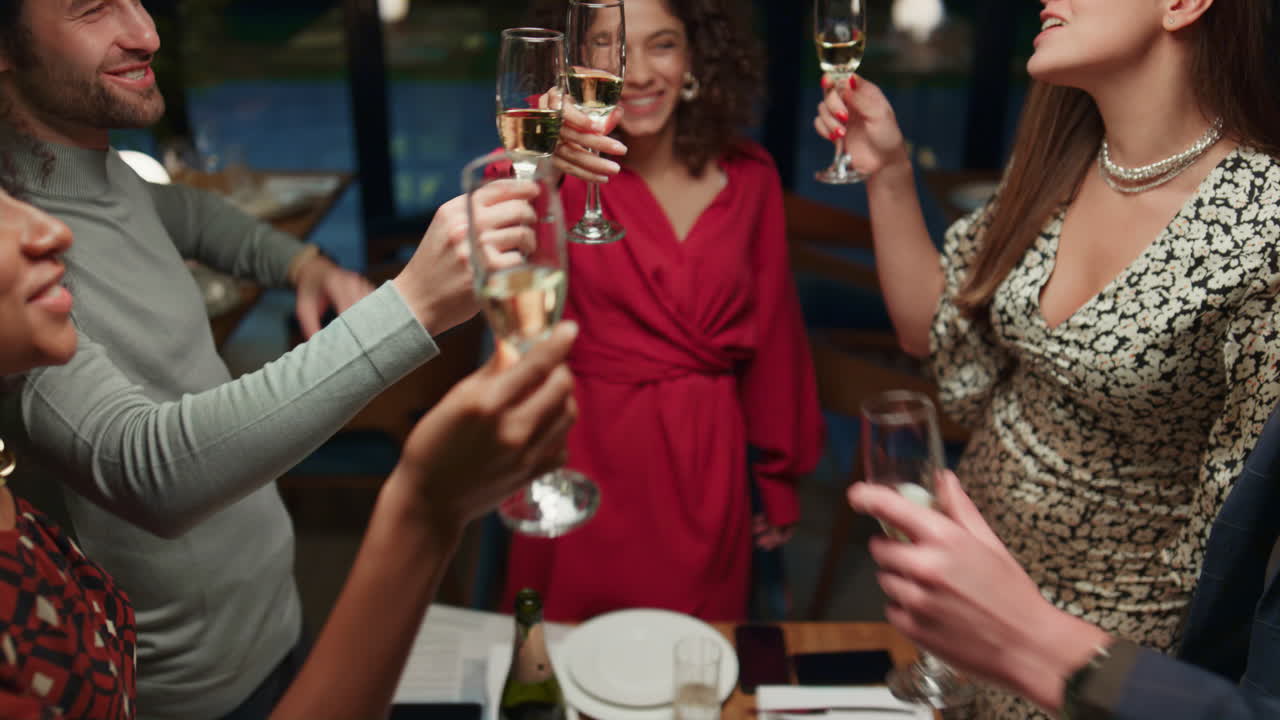 Young people party together drinking alcohol. Friends clinking glasses in cafe.