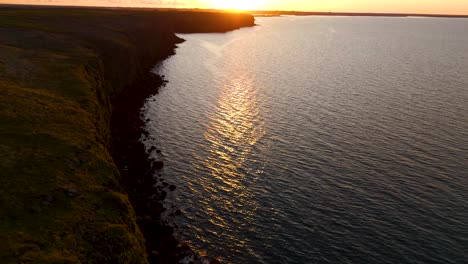 Inclinación-De-Los-Acantilados-De-Islandia,-Con-El-Reflejo-De-La-Puesta-De-Sol-En-El-Océano-Atlántico.