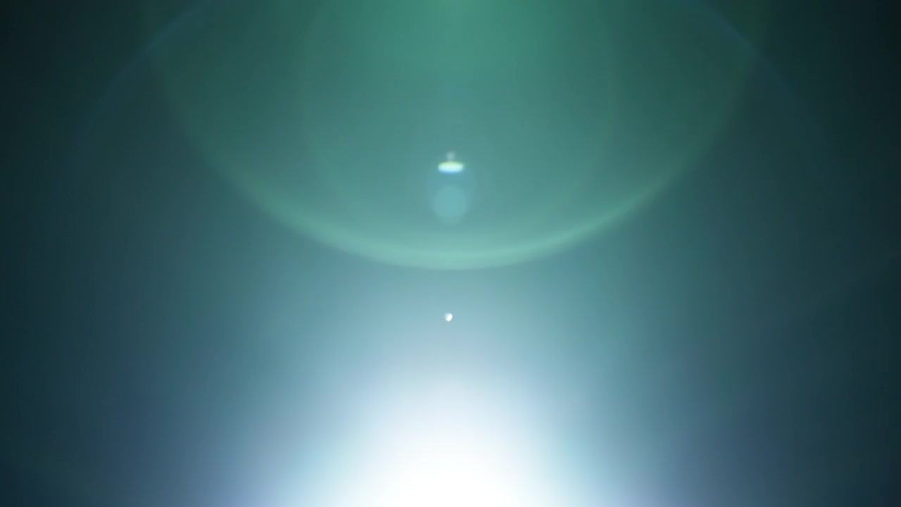 Green lens flares overlay fading out into black background. Slow motion