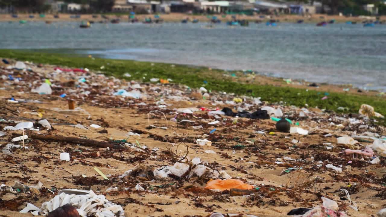 Close up shot of plastic bottles,waste and dirt polluting sandy beach in Vietnam