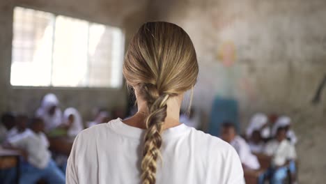 not recognizable white caucasian blonde girl teaching as a volunteer in african school with little children