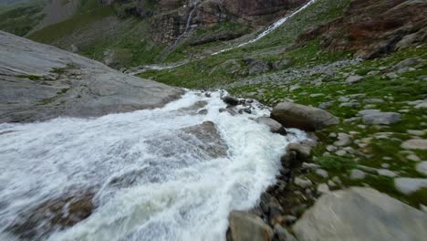 drone de carreras volando sobre una corriente de agua que fluye en el glaciar fellaria en valmalenco de valtellina, italia