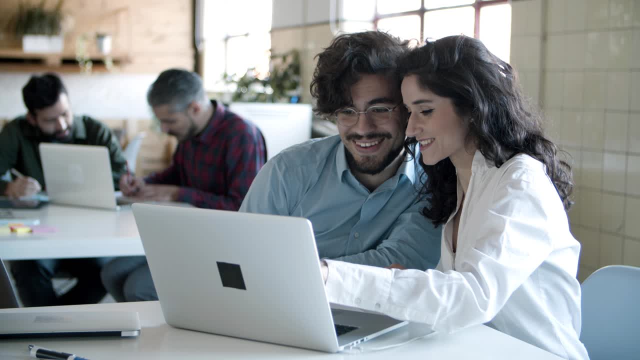 colegas jóvenes sonrientes trabajando con computadoras portátiles