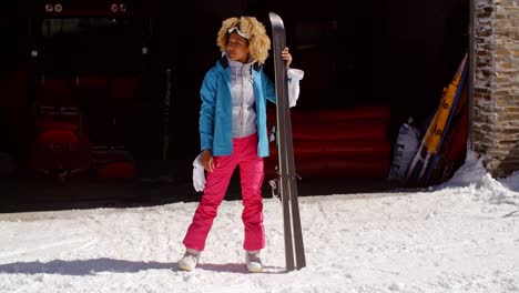 mujer joven confiada en traje de nieve con esquís