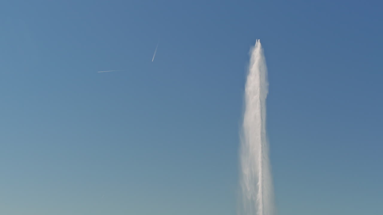 Peaceful morning in Geneva with the iconic Jet d’Eau rising from the lake, calm waters reflecting the clear sky, and the city slowly coming to life in the morning light.