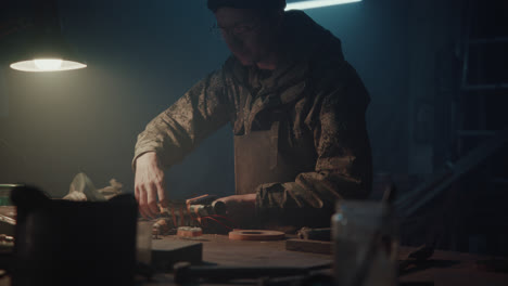 a bombmaker assembles a bomb in his workshop at night