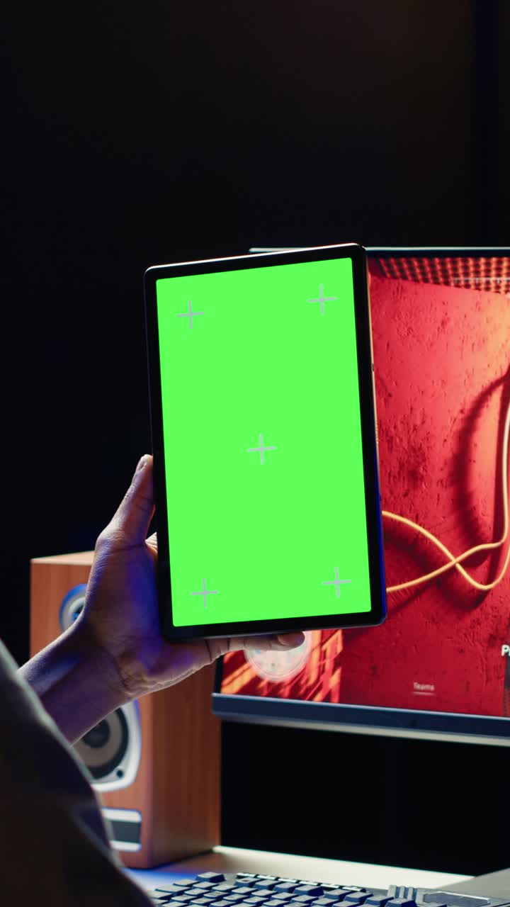 Vertical video Man watching videos on green screen tablet while playing PC games
