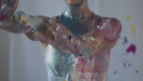 the female model posing on a white backdrop covered in colorful paint