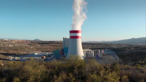 Drone-Steam-chimney-coal-fired-power-station-Dolly-shot-Sunset-trees-foreground