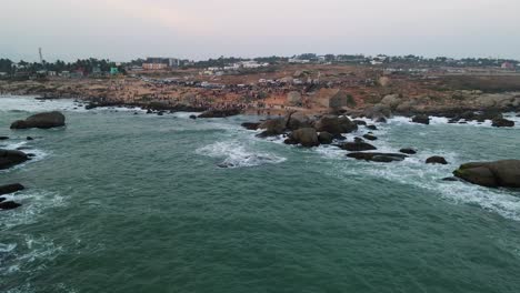 aerial drone shot capturing the peaceful sunset over kanyakumari’s ocean and vibrant urban life.