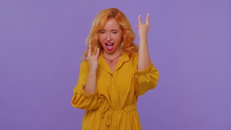 overjoyed redhead girl showing rock n roll gesture by hands, cool sign shouting yeah with crazy face