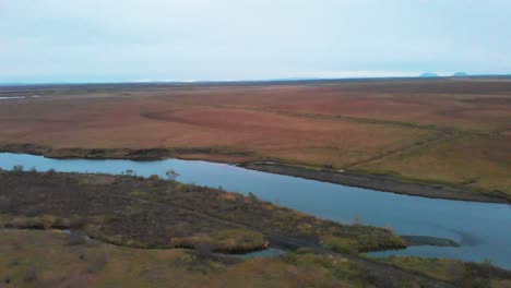 río en un paisaje nórdico áspero azotado por el viento con llanuras, islandia