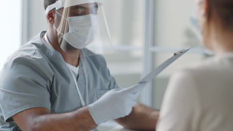 doctor in protective uniform giving consultation to patient