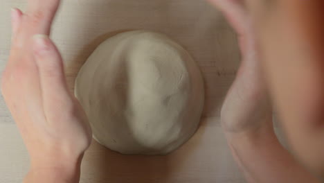 skilled artist preparing clay with her hands for working on throwing wheel