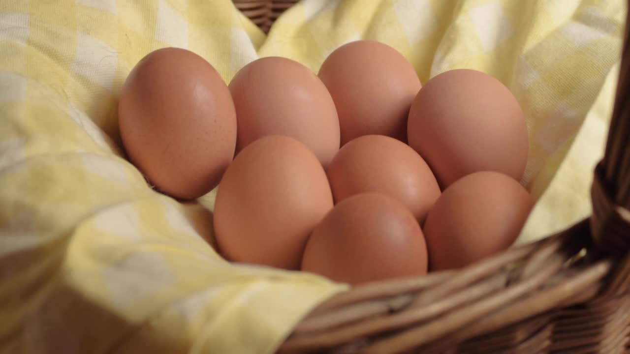 Fresh brown eggs in a woven basket tilt shot