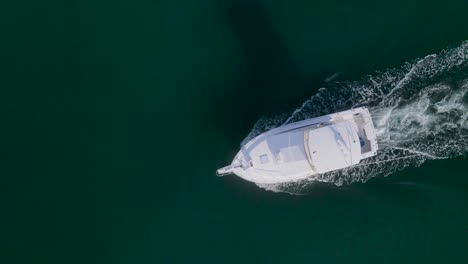 Top-down-orbit-of-white-fishing-boat-driving-with-small-wake