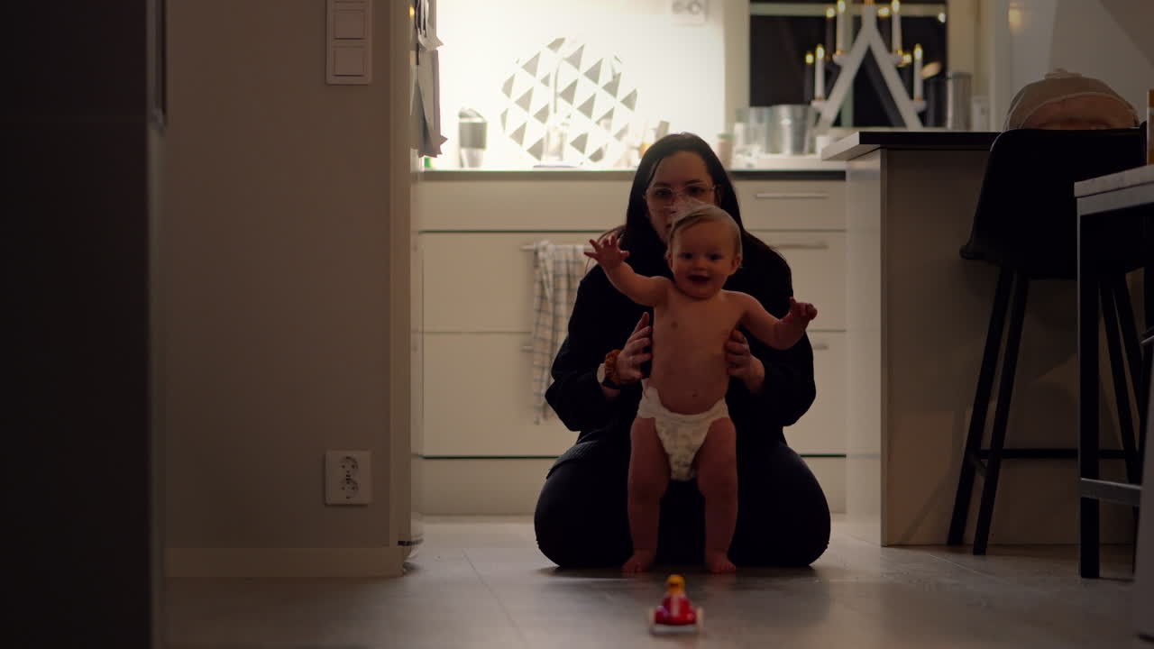 Baby boy taking his first steps with his mother at home. Slow motion