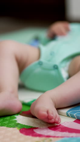 little baby in light blue clothes lies on bed with his feet to the camera. sleeping child slightly moving tiny feet. blurred backdrop. vertical video