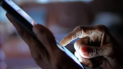 elderly person using smartphone at night