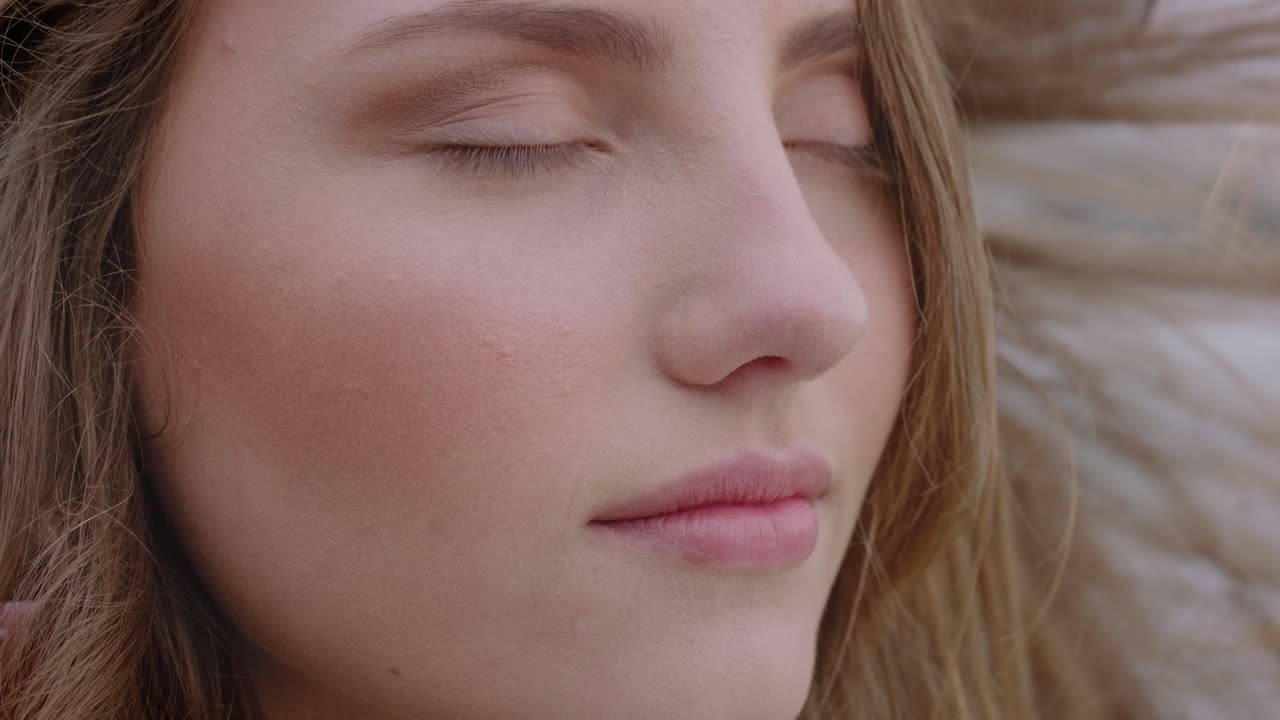 retrato de cerca de una mujer hermosa sonriendo disfrutando de la playa relajándose en la orilla del mar el viento soplando el cabello explorando un estilo de vida tranquilo y despreocupado