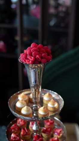elegant three-tiered dessert stand with raspberries and mini tarts