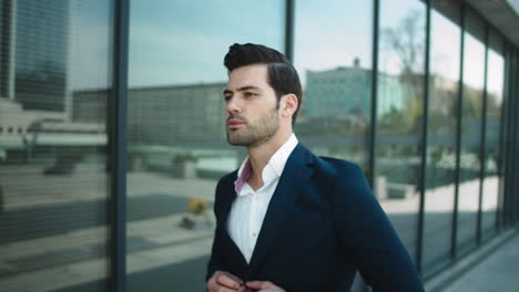 portrait businessman walking in suit. man checking time on wrist watch outside