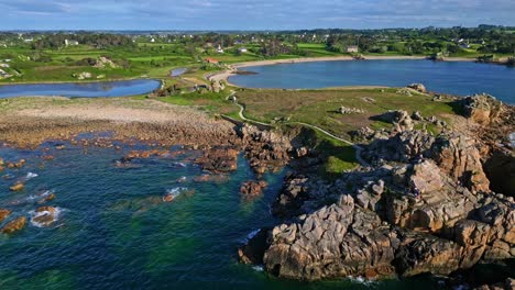 panning drone movement of the site du gouffre coastal's rocky outcrops surrounded by seawater on a small peninsula, plougrescant, côtes-d'armor, brittany, france