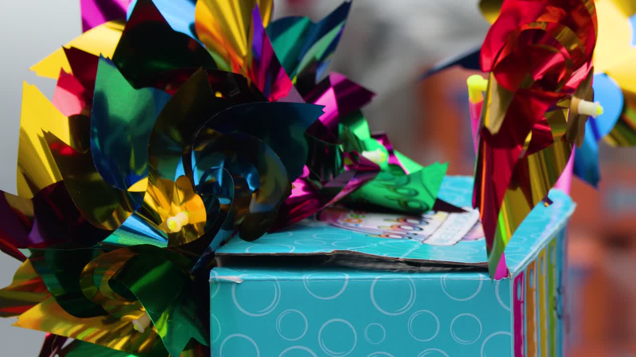 Bright metallic pinwheels spin in sunlight on a market stall at a lively outdoor festival