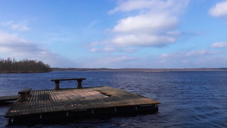 static shot of old wooden raft with bench float in blue water lake, latvia