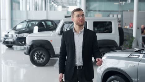 the young man turns on the music on the smartphone and starts dancing in the car shop