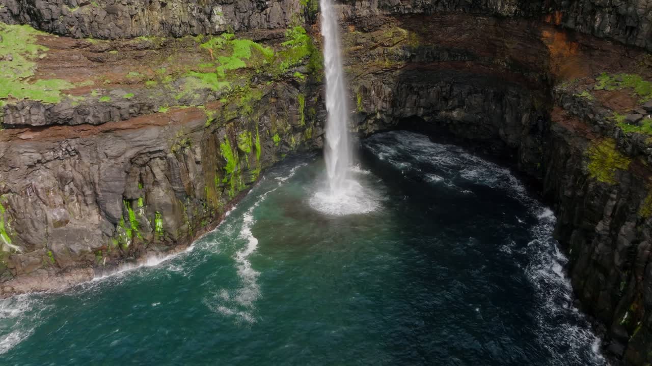 una impresionante cascada cae en una bahía turquesa en gasadalur, islas feroe