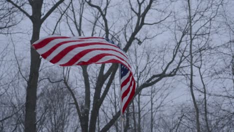 slow motion look at an american flag blowing in a winter flurry