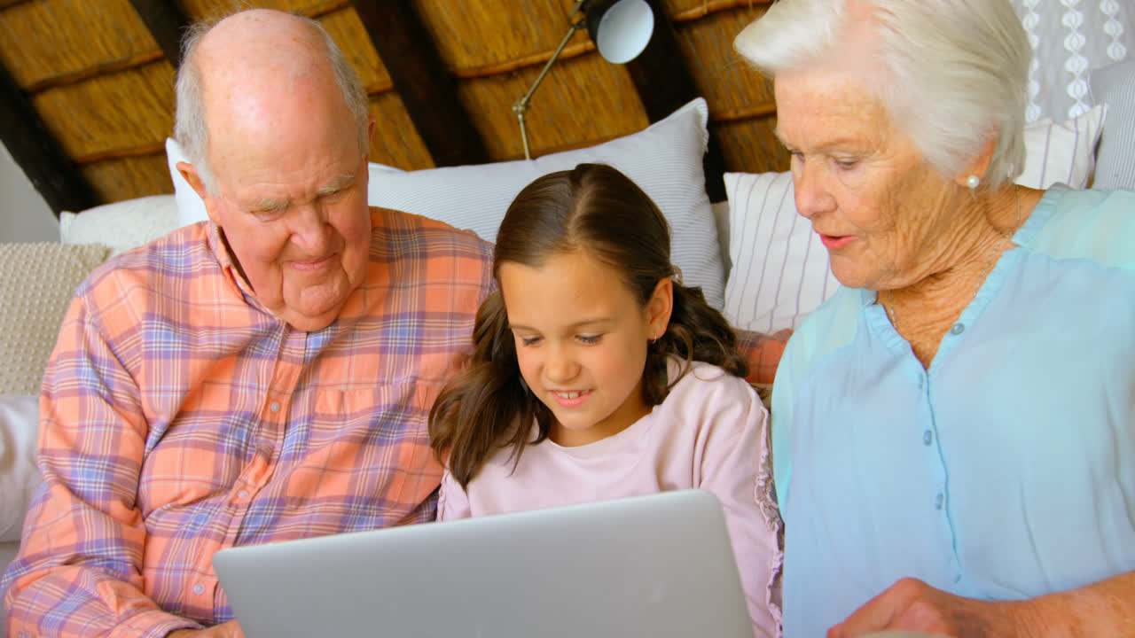 Front view of Caucasian multi-generation family using laptop in a comfortable home 4k