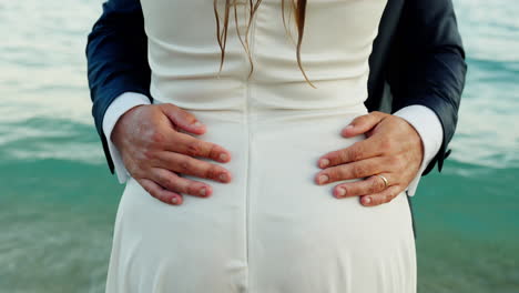 groom holding waist of bride on a wedding nearby sea