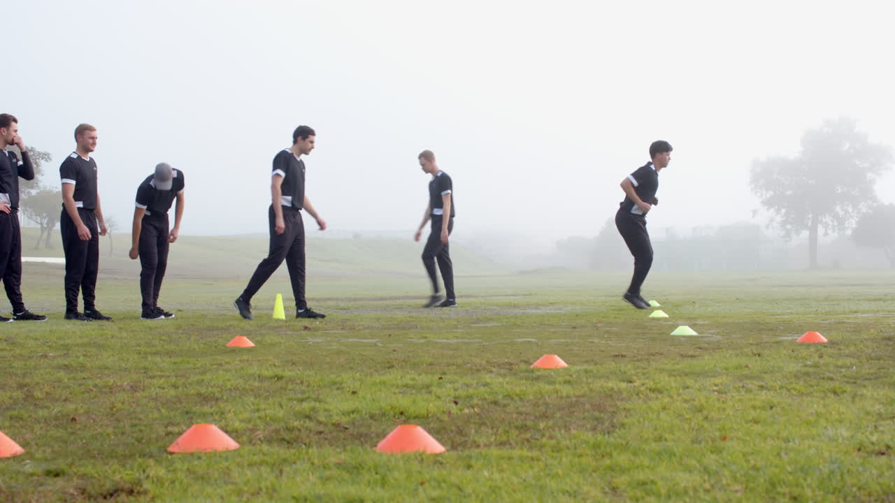 Training for cricket, group of men running drills on field with cones