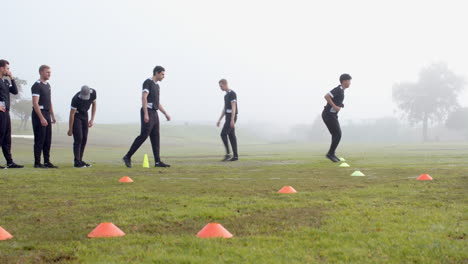 Training for cricket, group of men running drills on field with cones