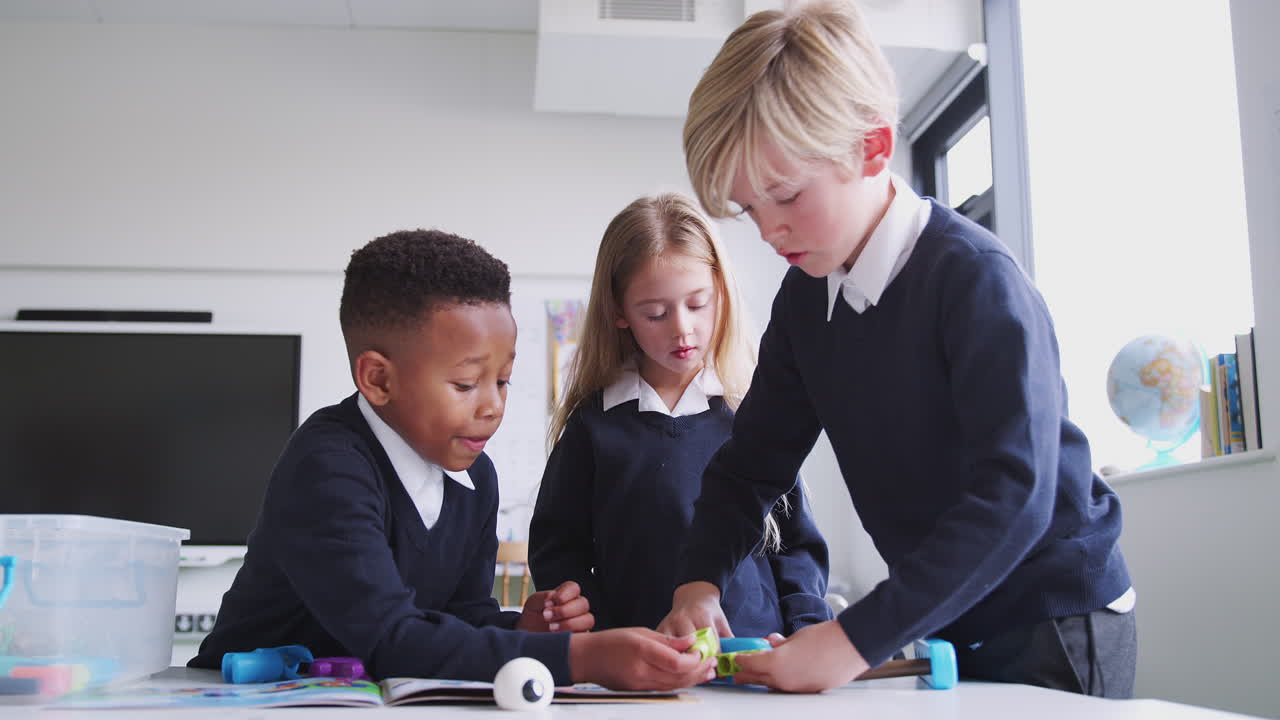 Three primary school children working with construction toy in classroom, close up, low angle