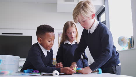 three primary school children working with construction toy in classroom, close up, low angle