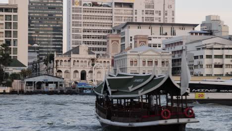 traditional boat moves across urban waterfront