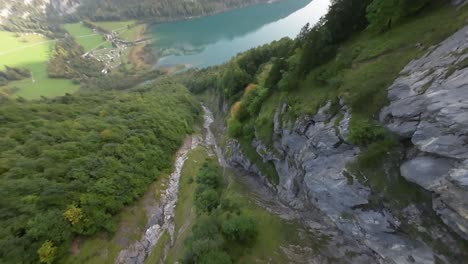 fpv drone descend over switzerland mountain gorge and reach turquoise water lake