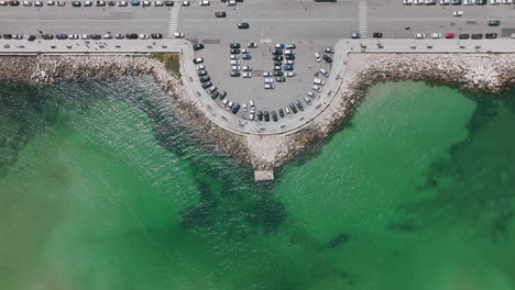 antena estática de arriba hacia abajo de un lugar de pesca y observación en el mar adriático en la ciudad de bari, italia con automóviles conduciendo por