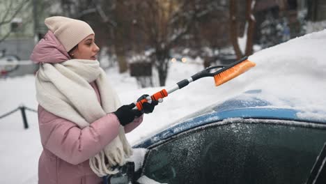 mujer quitando la nieve de un coche en invierno