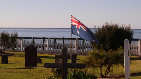 una tumba de excavadores de la guerra mundial con la bandera australiana ondeando orgullosamente sobre su lápida en un cementerio con vistas al océano