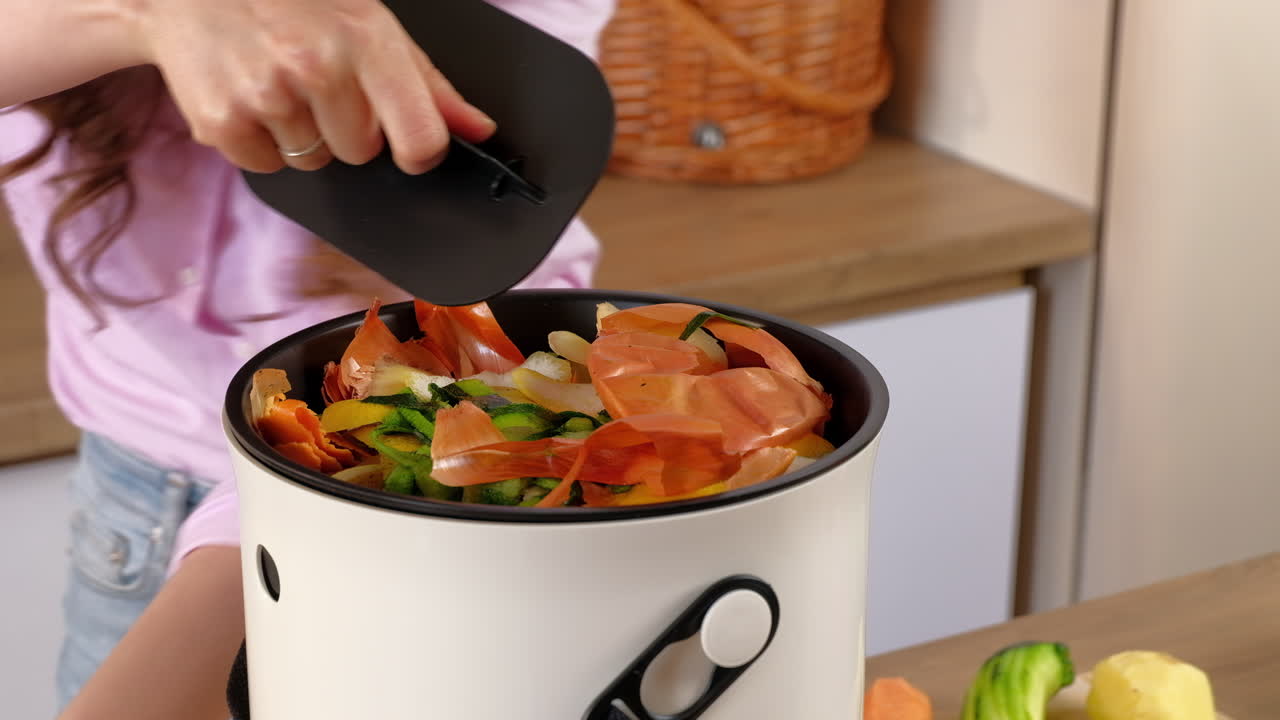 Woman recycling organic waste by composting vegetables peels in the Bokashi in the kitchen